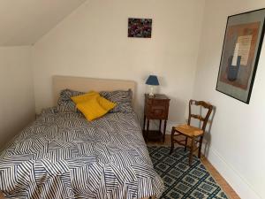 sypialnia z łóżkiem z żółtą poduszką i krzesłem w obiekcie maison delalonde Autun centre charmant meublé 5 places w mieście Autun