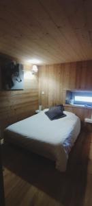 um quarto com uma cama grande numa parede de madeira em Appartement au rez de jardin d'une villa Mexicaine avec jacuzzi em Barcelonnette
