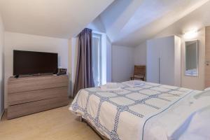 a bedroom with a bed and a flat screen tv at Saija Attico in Pozzallo