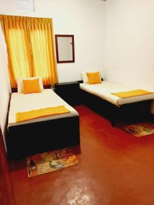 2 camas en una habitación con suelo rojo y cortinas naranjas en Coco Garden Villas, en Hikkaduwa