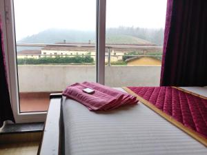 uma cama com uma toalha em frente a uma janela em Forest Gate em Ooty