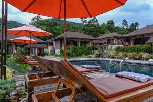 a group of chairs and umbrellas next to a pool at Cascade Tara in Na Mueang
