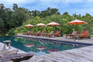 uma piscina com mesas, cadeiras e guarda-sóis em Cascade Tara em Na Mueang