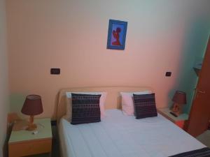 ein Schlafzimmer mit einem weißen Bett mit zwei Tischen und zwei Lampen in der Unterkunft Casa Amizade B&B in Pedra Badejo