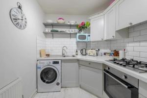 a white kitchen with a washing machine and a clock at Spacious 2 Bedroom Flat in Wandsworth in London