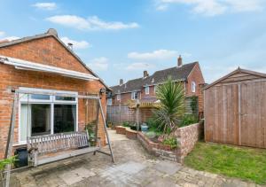 a brick house with a garden and a fence at 2 Benhall Green in Saxmundham