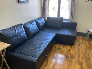 a black leather couch in a living room with a table at 133 A Park Road in Manchester