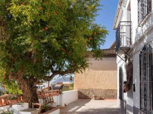 a tree next to a building with red apples on it at Casa de Las Granadas in Nigüelas