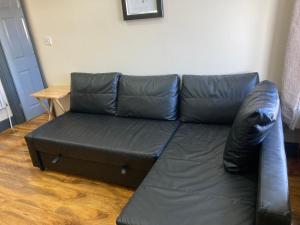 a black leather couch in a living room at 133 A Park Road in Manchester