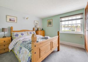 a bedroom with a wooden bed and a window at Puddingmoor Cottage in Beccles