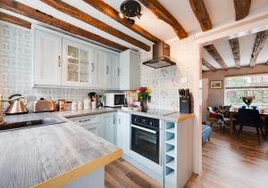 a kitchen with white cabinets and a counter top at Puddingmoor Cottage in Beccles