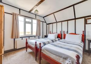 two beds in a room with two windows at Beach House in Southwold