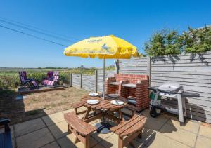 a picnic table with a grill and a yellow umbrella at Beach House in Southwold