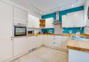 een keuken met witte kasten en blauwe muren bij Flat 1 Eversley Cottage in Southwold