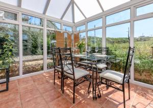 a conservatory with a glass table and chairs on a patio at Bryn in Abersoch