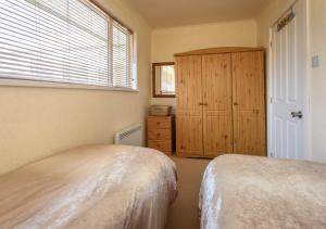 1 dormitorio con 2 camas, armario y ventana en Bryn, en Abersoch