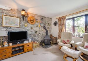 a living room with a tv and a stone wall at Bryncylla in Llangurig
