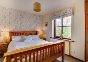 a bedroom with a wooden bed and two windows at Bwthyn Gwyn in Llanerchymedd