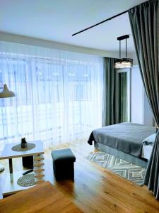 sypialnia z łóżkiem, stołem i oknami w obiekcie Apartamenty Suerte w Darłówku