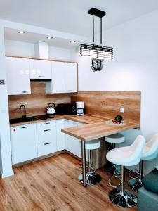 a kitchen with white cabinets and a wooden counter top at Apartamenty Suerte in Darłówko