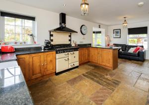 a kitchen with wooden cabinets and a stove top oven at Drws y Llan in Llanengan