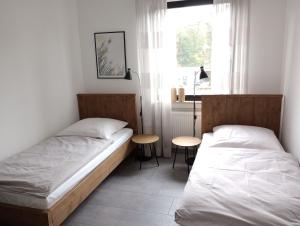 two beds in a room with a table and a window at Provinzial Ferienwohnung Walter in Wadgassen