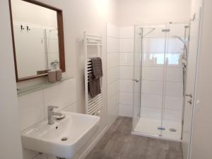 a white bathroom with a sink and a shower at Provinzial Ferienwohnung Walter in Wadgassen
