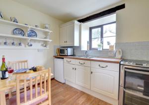 uma cozinha com armários brancos, um lavatório e uma janela em The Barn em Llanerchymedd