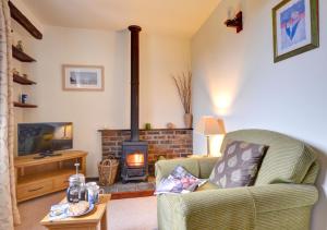 a living room with a fireplace and a chair and a television at The Barn in Llanerchymedd