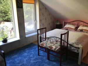 a bedroom with a bed with two chairs and two windows at Šturmų Sodyba in Ventė