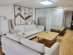 a living room with a white couch and a table at Chaoyang Joy City Hardcover Apartment in Beijing