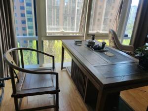 una mesa de madera y una silla en una habitación con ventanas en Chaoyang Joy City Hardcover Apartment, en Beijing