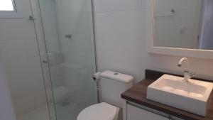 a bathroom with a shower and a toilet and a sink at Residencial Lazzari Apto 402 in Arroio do Sal +3 photos