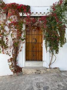 een houten deur met rode bloemen op een wit gebouw bij CUEVAS DEL PEÑÓN - Loft Torreón in Grazalema