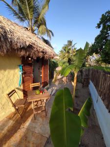 une petite maison avec une table et un toit de chaume dans l'établissement Pitico Chalé - Icaraí Kite Village, à Icaraí
