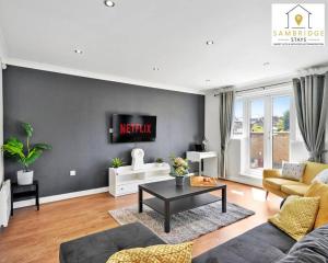 een woonkamer met een bank en een tv aan de muur bij The Penthouse 3 Bedroom Apartment by Sambridge Stays in Watford