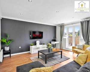 a living room with a couch and a tv on a wall at The Penthouse 3 Bedroom Apartment by Sambridge Stays in Watford