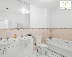 a bathroom with two sinks and a toilet and a bath tub at The Penthouse 3 Bedroom Apartment by Sambridge Stays in Watford