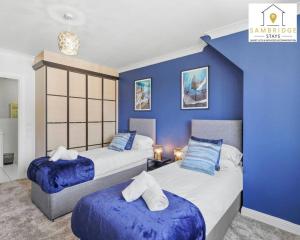 twee bedden in een kamer met blauwe muren bij The Penthouse 3 Bedroom Apartment by Sambridge Stays in Watford