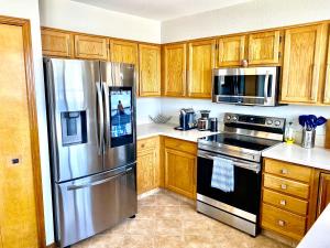 Una cocina con gabinetes de madera y un refrigerador de acero inoxidable. en Artsy Home close to USAFA with Fireplace and Patio, en Colorado Springs