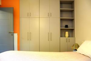 1 dormitorio con armarios blancos y pared de color naranja en Olive and Orange Apartment, en Mystras