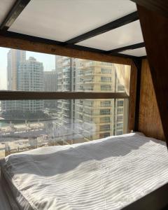 Bett in einem Zimmer mit einem großen Fenster in der Unterkunft Lunar Hostel Plus in Dubai