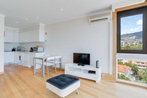 a living room with a large window and a kitchen at Funchal View Apartment in Funchal