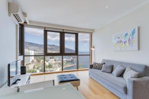 a living room with a couch and a large window at Funchal View Apartment in Funchal