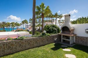 una chimenea de piedra en un patio con palmeras en Casa Silvia, casa con jardín y vista al mar, en Costa Calma