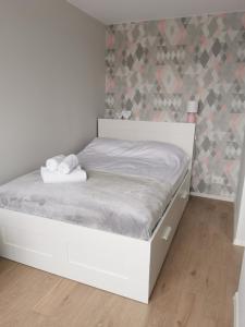 białe łóżko w pokoju ze ścianą w obiekcie Apartament Manhattan w Kłodzku