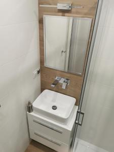 een badkamer met een witte wastafel en een spiegel bij Apartament Manhattan in Kłodzko