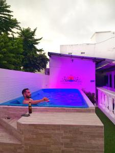 a man in a swimming pool with a bottle of beer at Comunidad Calle 13 Hotel Boutique in Santa Marta