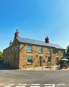 un vecchio edificio in mattoni con ombrello verde di The Devonshire Arms a Eckington