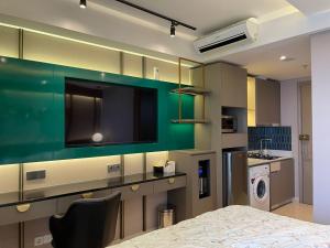 Gold Coast Apartemen PIK by Dluxx في جاكرتا: مطبخ مع طاولة وتلفزيون وغرفة غسيل